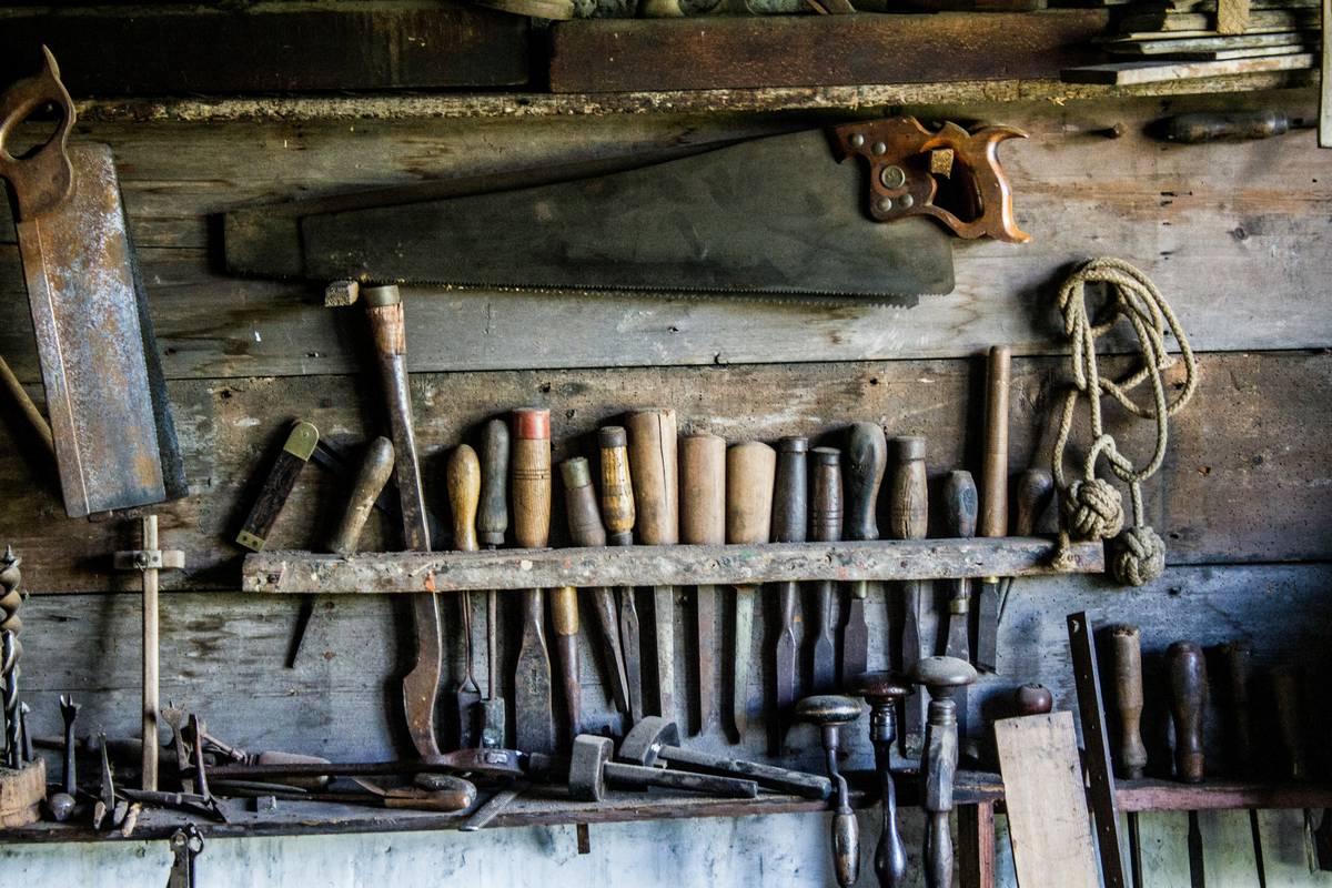basic power tools needed for woodworking laid out on a workbench including circular saw, drill, sander, and jigsaw